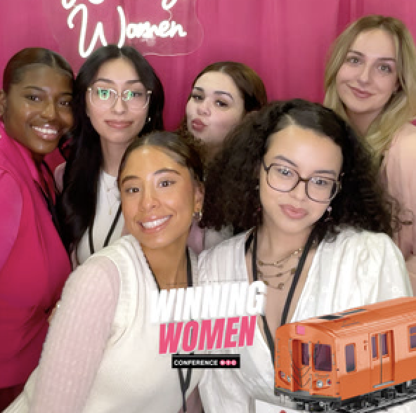 Group posing in front of a branded backdrop with a neon sign